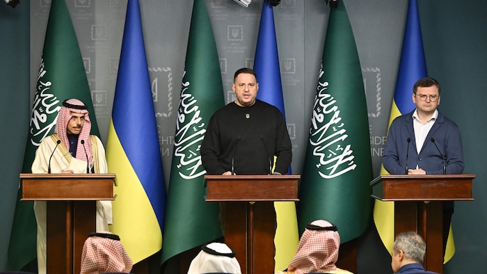 Faisal bin Farhan Al-Saud, Andriy Yermak et Dmytro Kouleba sont côte à côte derrière des lutrins. Des drapeaux de l'Ukraine et de l'Arabie saoudite se trouvent derrière eux.