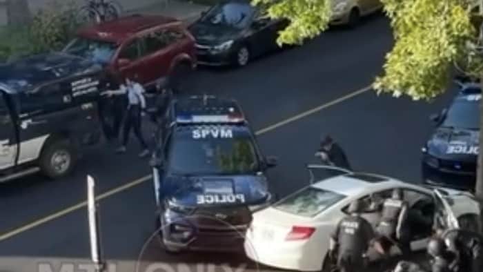 Silya Medkour, à côté d'une voiture de police, est amenée par un policier dans un fourgon cellulaire.