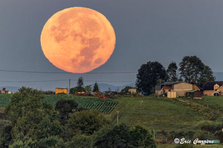 Une lune similaire au-dessus d'une ferme.