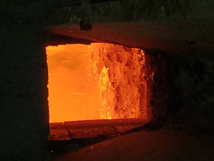 A view into an orange-glowing furnace. Molten lead can be seen inside.