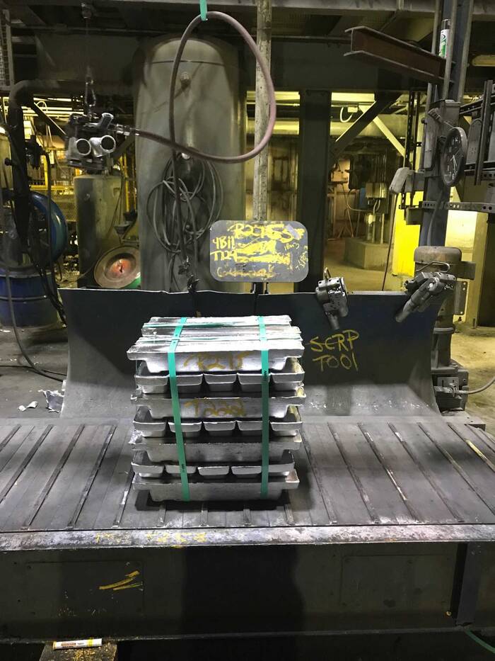 A stack of silver lead ingots sits on a conveyor in the refinery area.