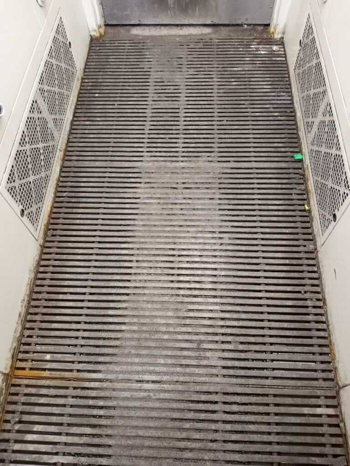 A photo of a slotted floor in the airshower where dust is blown off of employees after their shift.
