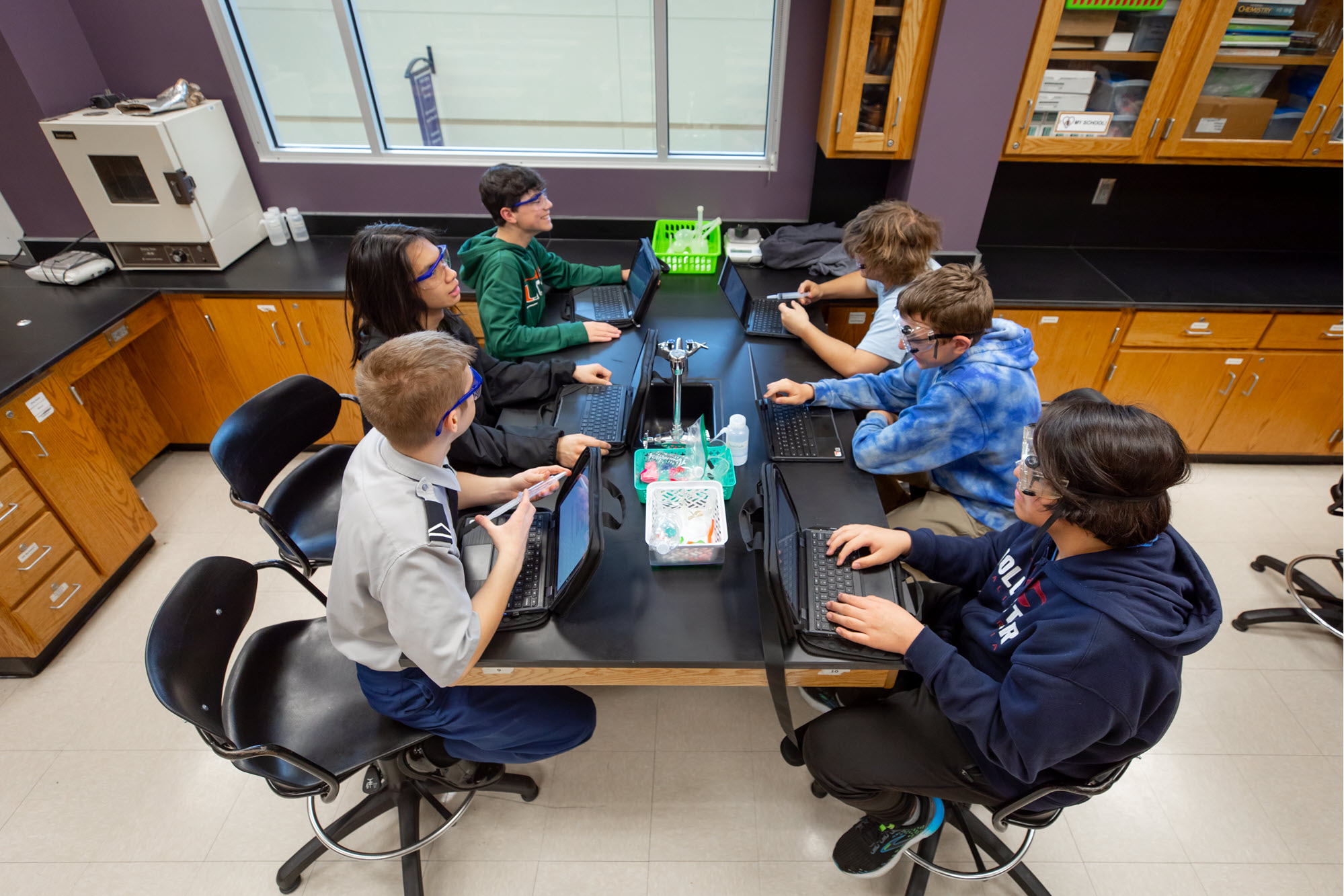 A group of students sitting around a table in a classroom comparing notes