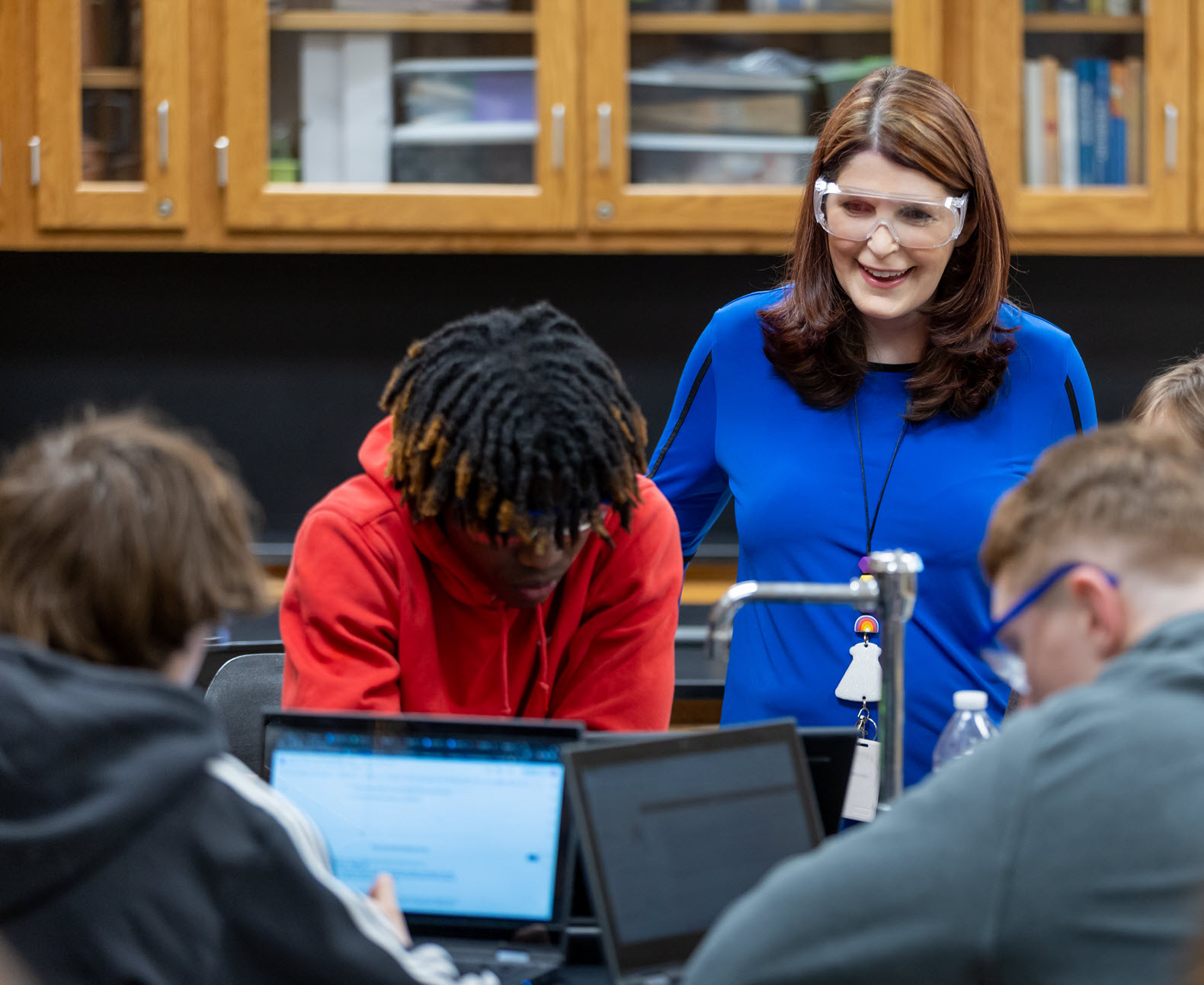 A female chemistry teacher works with a group of students in a classroom setting 